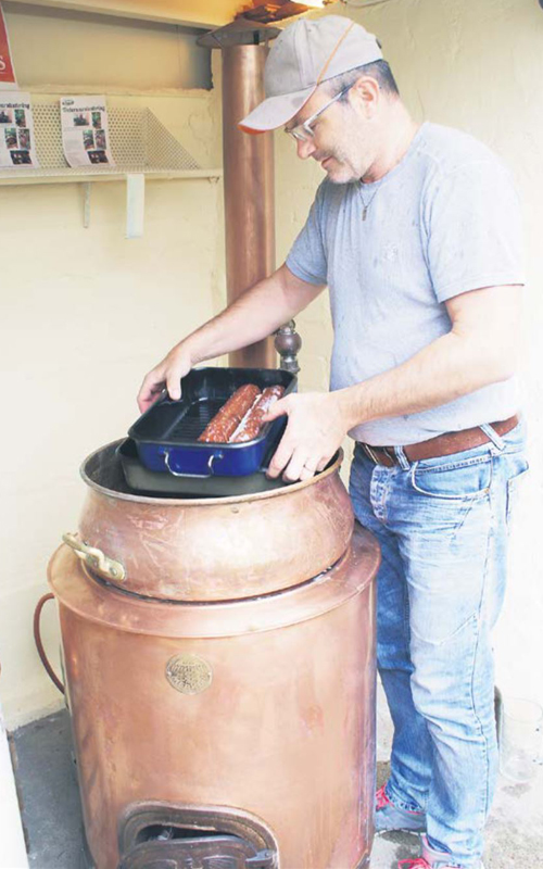 Das Foto zeigt Tinu Mürset aus Twann, der Treberwürste im alten Brennhafen zubereitet.